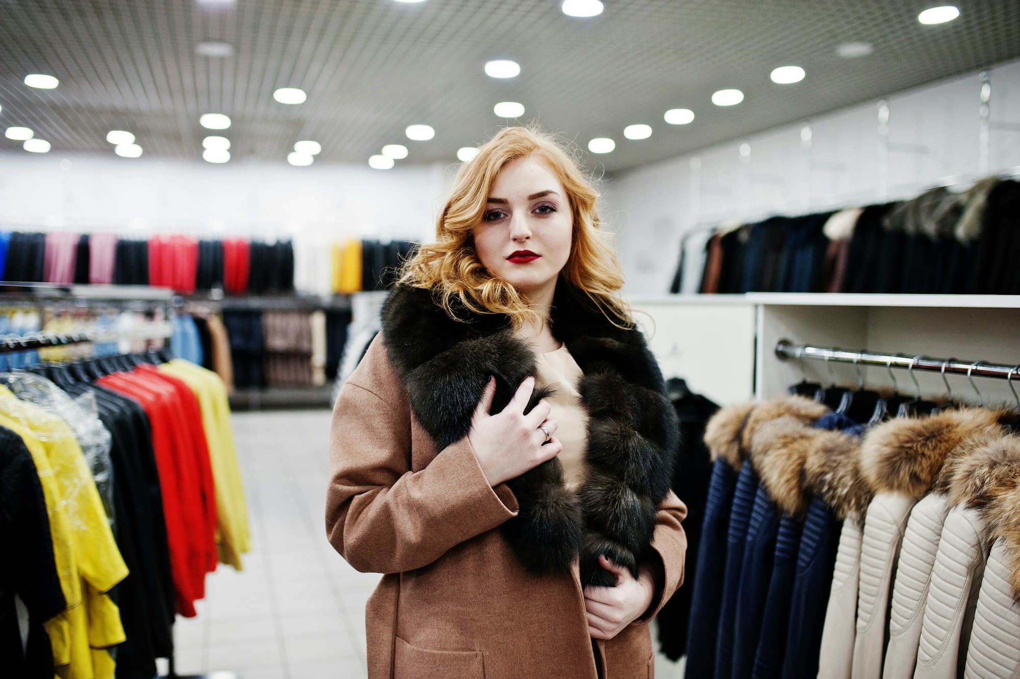 Elegance blonde girl in fur coat at the store of fur coats and leather jackets.